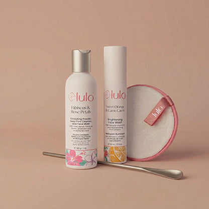 Luo Skin products including a bottle, an airless pump, a measuring spoon and round cleansing pad on a beige background